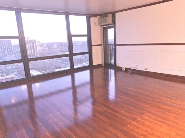 a view of an empty room with wooden floor and a window