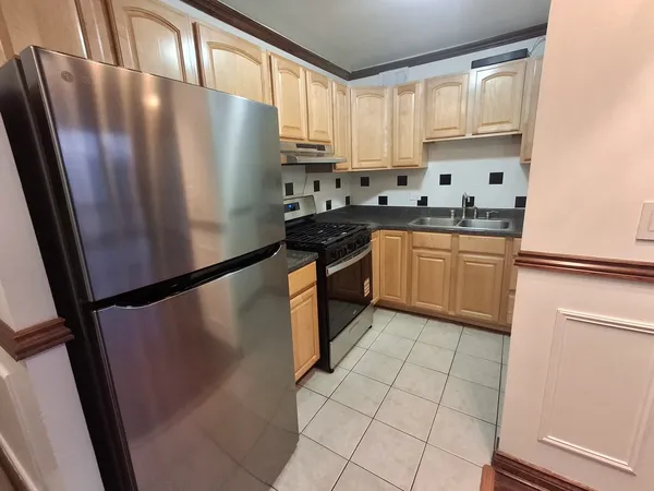 a kitchen with granite countertop a refrigerator a sink a stove and white cabinets