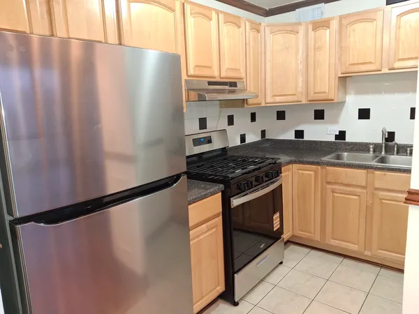 a kitchen with stainless steel appliances granite countertop white cabinets a refrigerator and a sink