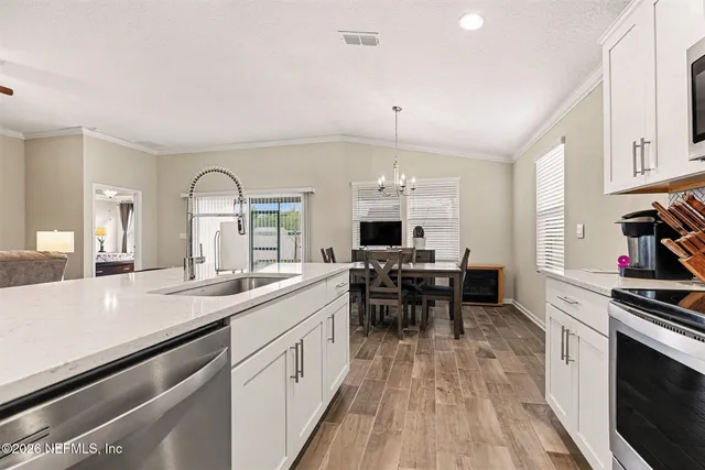 a kitchen with stainless steel appliances granite countertop a sink a stove a refrigerator and chairs with wooden floor