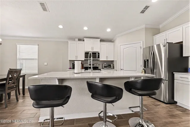 a kitchen with a refrigerator a stove a sink and chairs