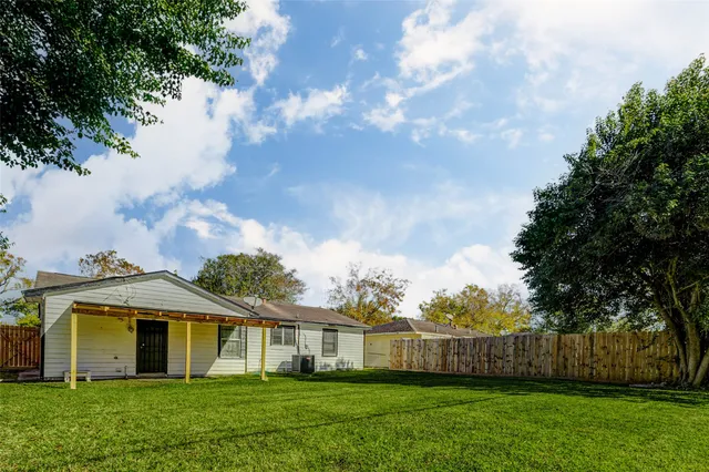 a view of a white house next to a yard with big trees
