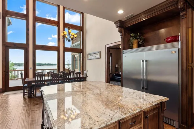 a kitchen with stainless steel appliances kitchen island granite countertop a refrigerator a stove and a dining table with wooden floor