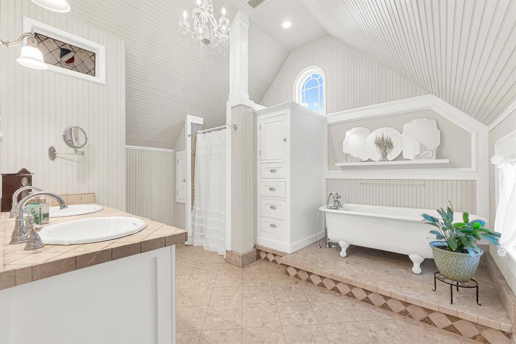 1425 Lone Star Road Celina, TX 75009 - Photo 15 of 40 A clawfoot soaking tub, soaring beadboard ceiling, and arched window fill the bath with timeless charm and soft natural light. Unwind with a long soak at the end of the day and enjoy a space designed for quiet moments of relaxation.