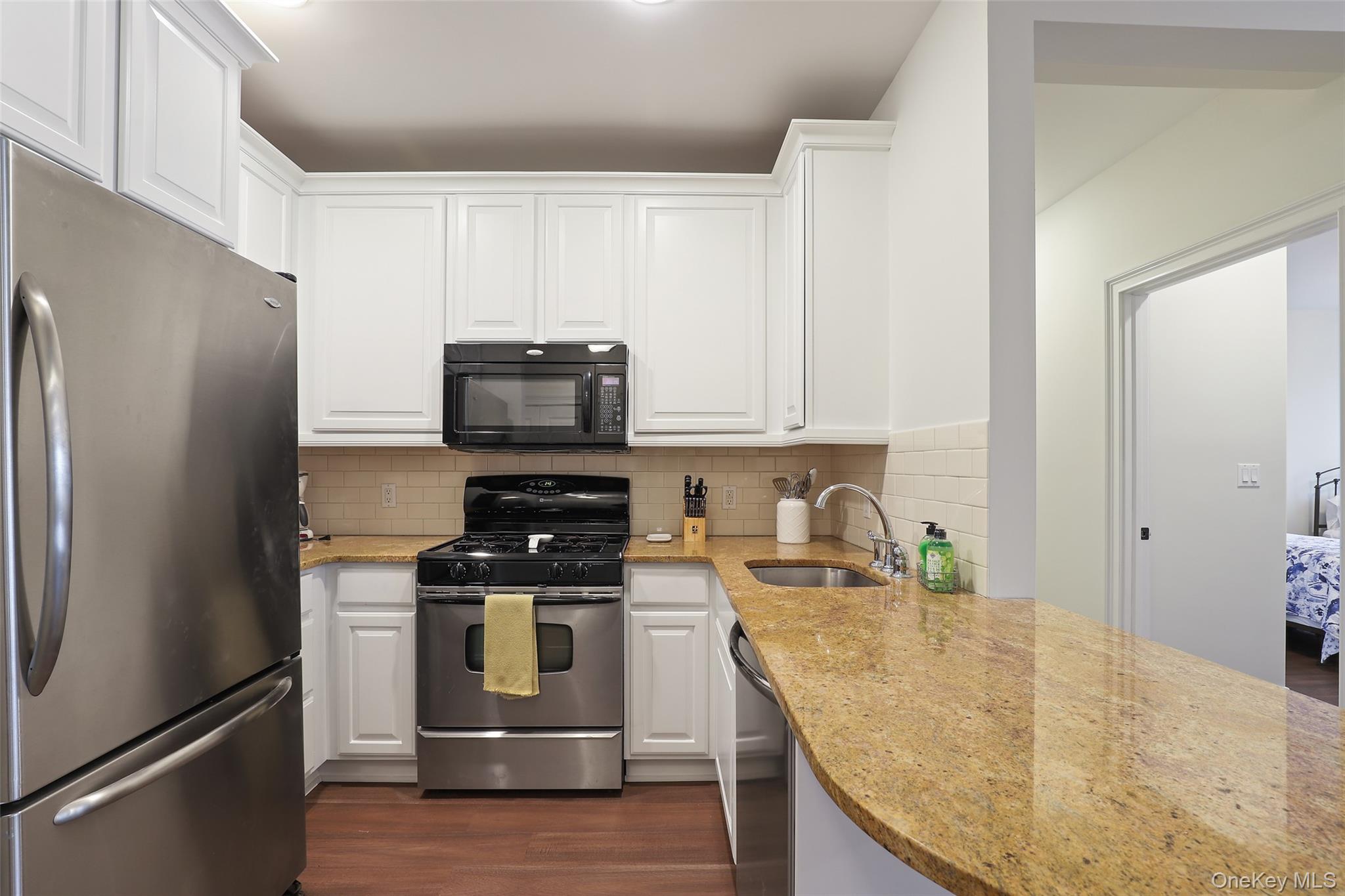 a kitchen with granite countertop a refrigerator stove and microwave