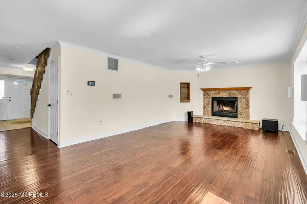 a view of an empty room with wooden floor fireplace and a window