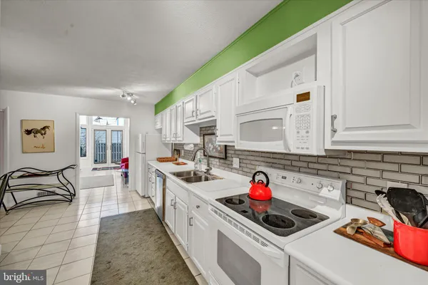 a kitchen with a refrigerator a sink dishwasher a dining table and chairs with wooden floor