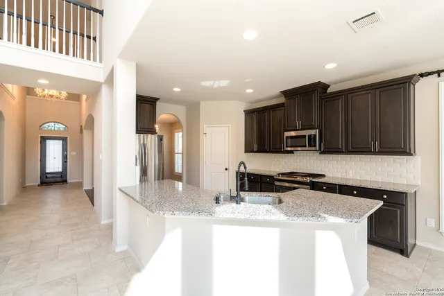 a large kitchen with stainless steel appliances granite countertop a large counter top a stove a sink a refrigerator and a granite counter tops