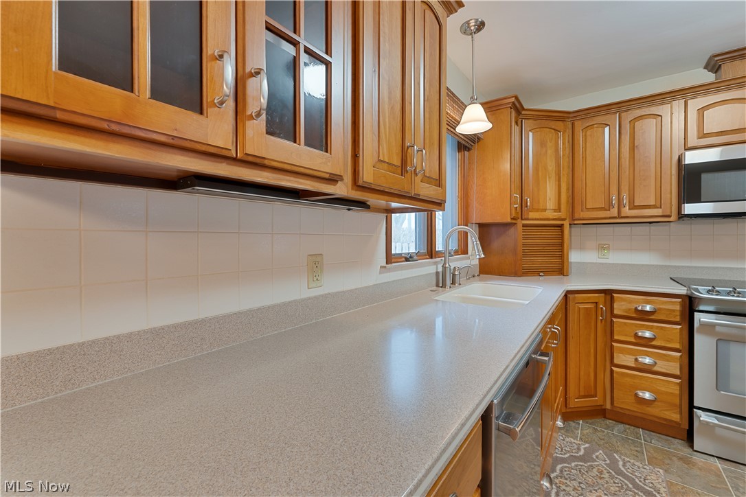6599 Struthers Road Youngstown, OH 44514 - Photo 14 of 29 Kitchen featuring decorative backsplash, stainless steel appliances, glass fronted cabinets, and wood finish cabinetry