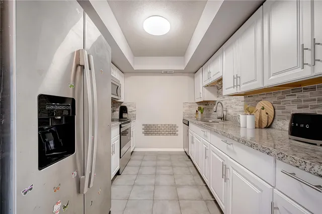a large kitchen with stainless steel appliances granite countertop a refrigerator and a stove