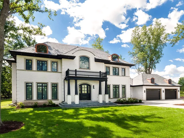 a front view of a house with a garden and trees