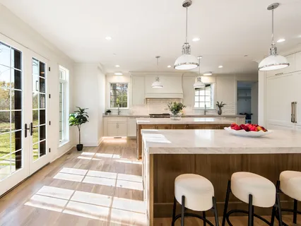 a large kitchen with kitchen island a large counter top space a sink a refrigerator and wooden floor
