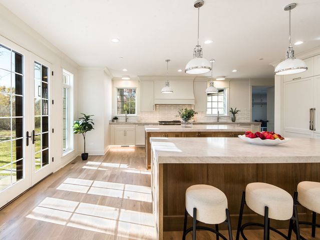a large kitchen with kitchen island a large counter top space a sink a refrigerator and wooden floor