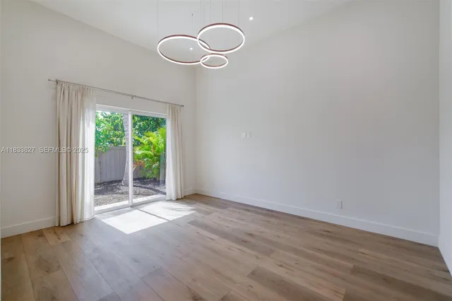 a view of an empty room with wooden floor and window