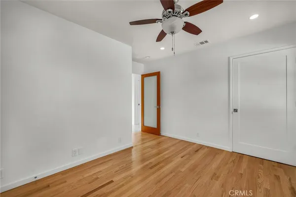 an empty room with wooden floor chandelier fan and closet area