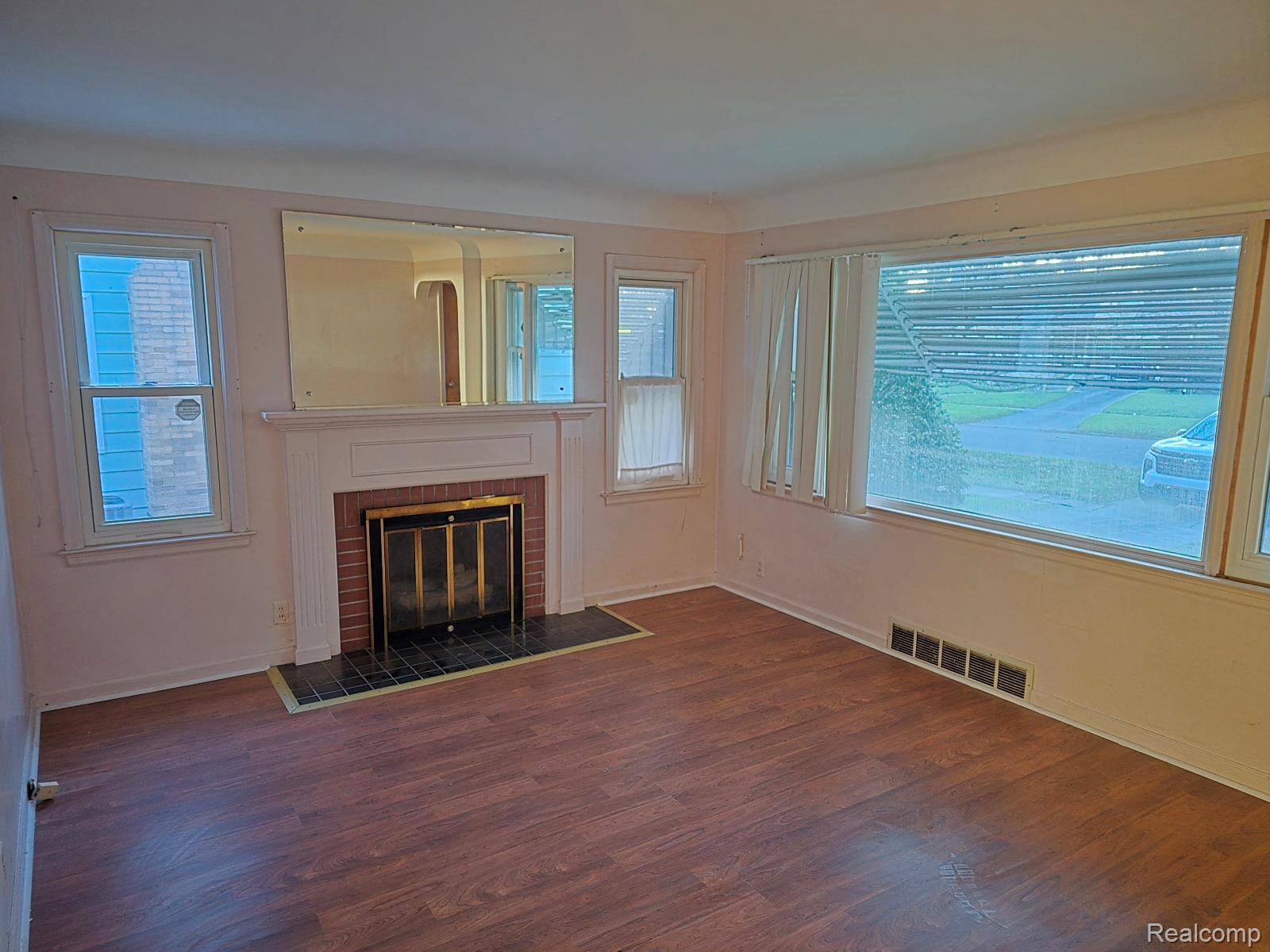 803 Commonwealth Avenue Flint, MI 48503 - Photo 10 of 15 Unfurnished living room featuring dark wood-style floors and a brick fireplace
