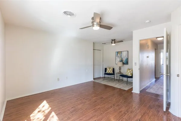 an empty room with wooden floor ceiling fan and windows