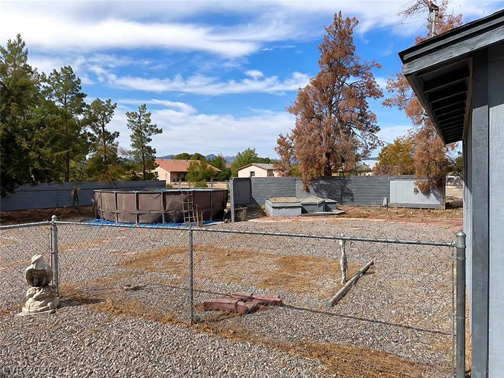 5561 Doubletree Road Pahrump, NV 89061 - Photo 19 of 19 An expansive gravel yard features an above-ground pool enclosed by a chain link fence.