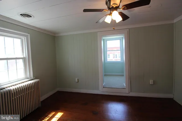 a view of empty room with wooden floor and fan