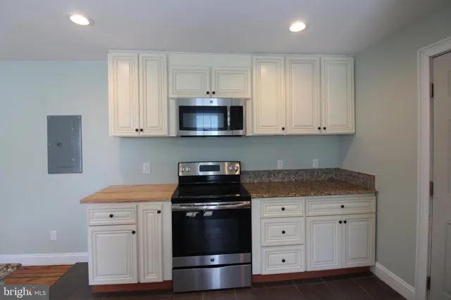 a kitchen with white cabinets and black appliances