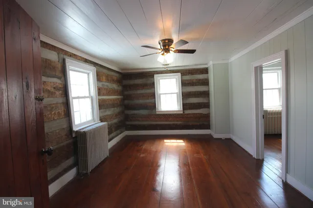 a view of hallway with wooden floor and fan