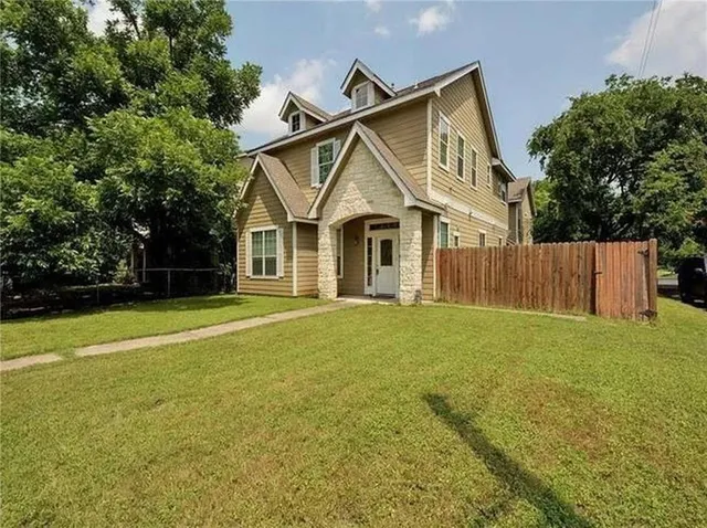 a front view of a house with yard and tree