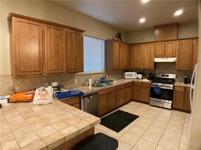a kitchen with stainless steel appliances kitchen island granite countertop a sink dishwasher stove top oven and cabinets