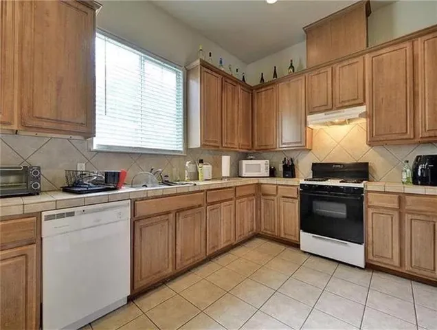 a kitchen with cabinets appliances a sink and a window