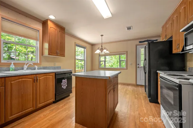 a kitchen with stainless steel appliances granite countertop a stove a sink dishwasher a refrigerator and a microwave oven with wooden floor