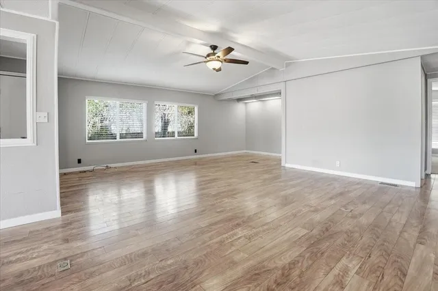 a view of an empty room with window and chandelier fan