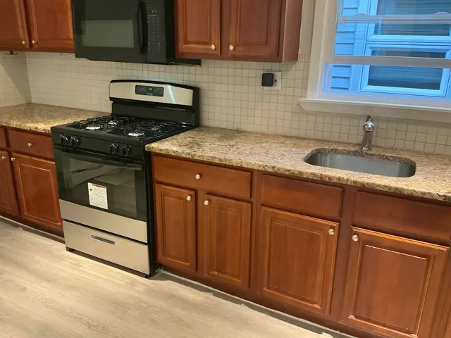 a kitchen with granite countertop stainless steel appliances a stove sink and cabinets