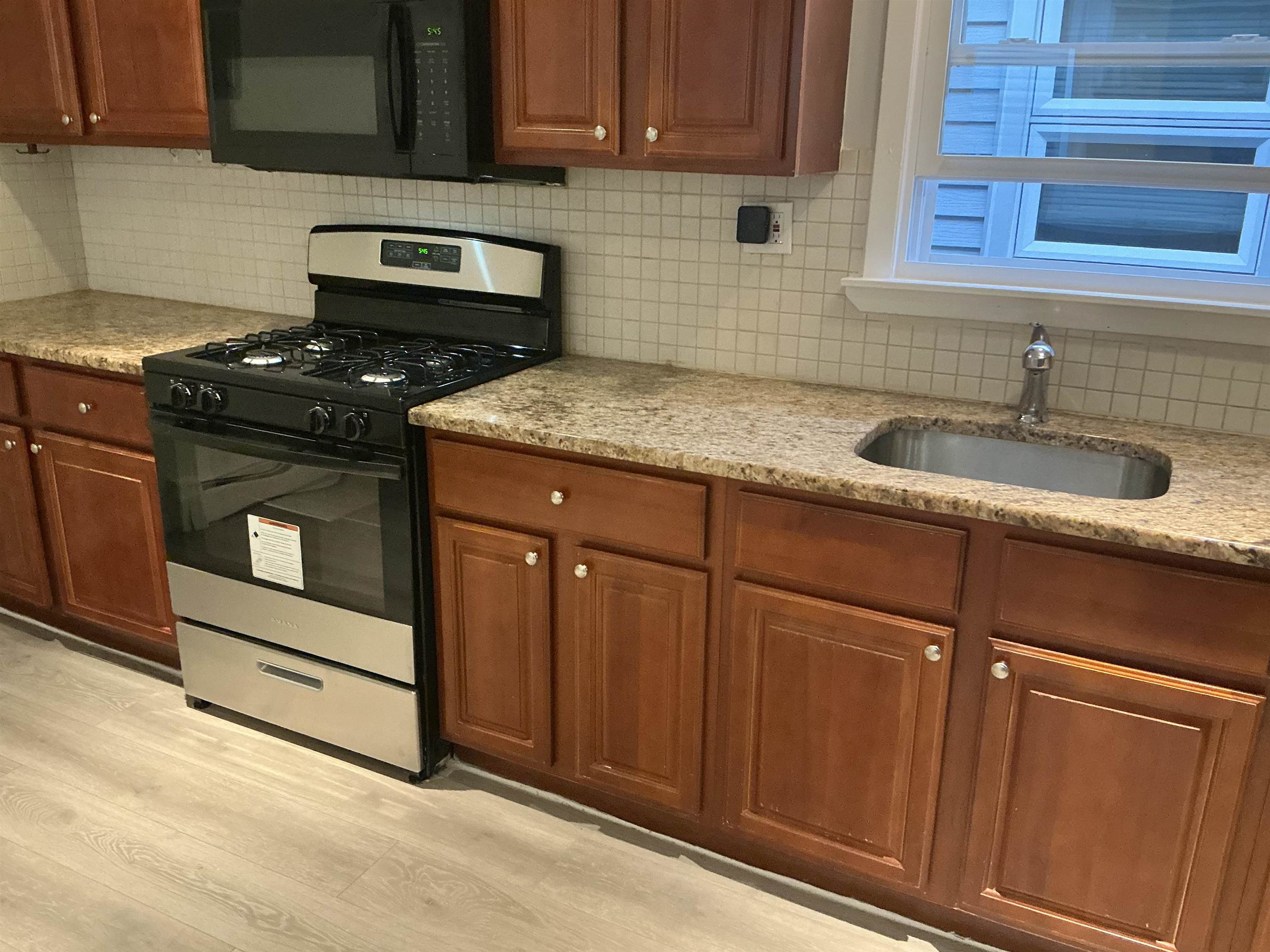 10 West Grand Street, Unit 2 Bayonne, NJ 07002 - Photo 2 of 13 a kitchen with granite countertop stainless steel appliances a stove sink and cabinets