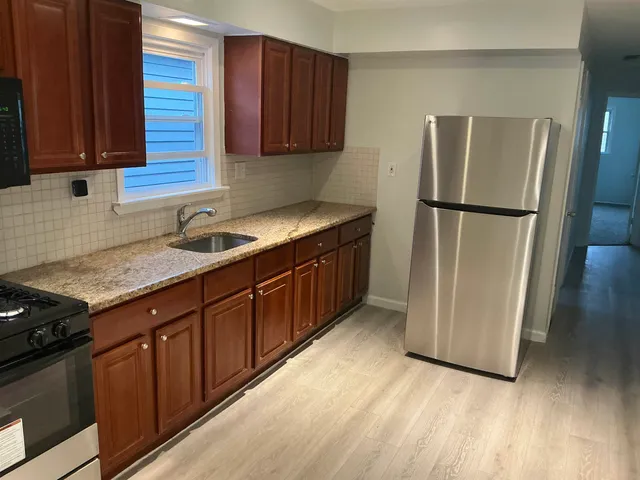 a kitchen with stainless steel appliances granite countertop a refrigerator a sink and wooden cabinets