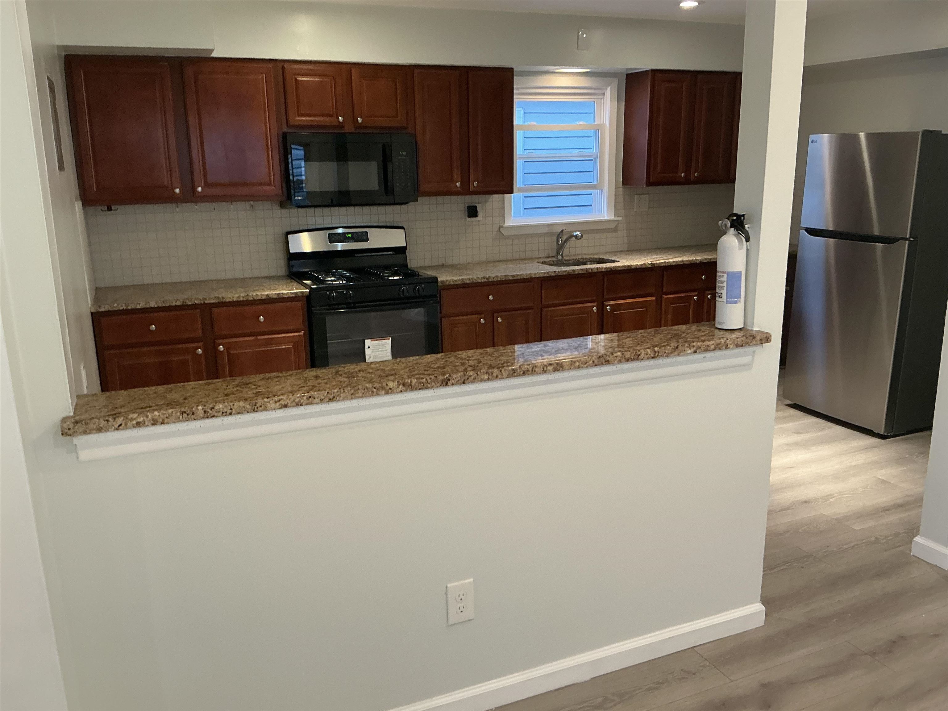 10 West Grand Street, Unit 2 Bayonne, NJ 07002 - Photo 4 of 13 a kitchen with stainless steel appliances granite countertop a refrigerator a stove a sink and a microwave