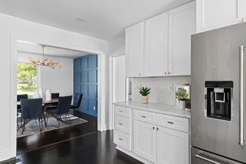 a kitchen with white cabinets and dining table chair