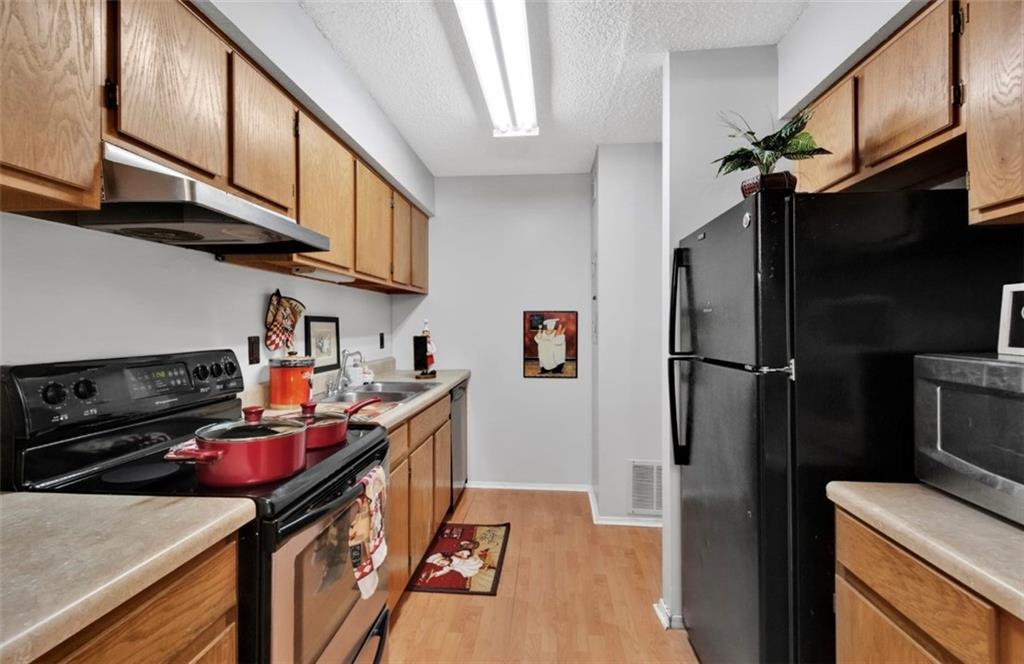 2411 Huntingdon, Unit 2411 Atlanta, GA 30350 - Photo 17 of 45 a kitchen with stainless steel appliances granite countertop a refrigerator a stove and a sink with wooden floor