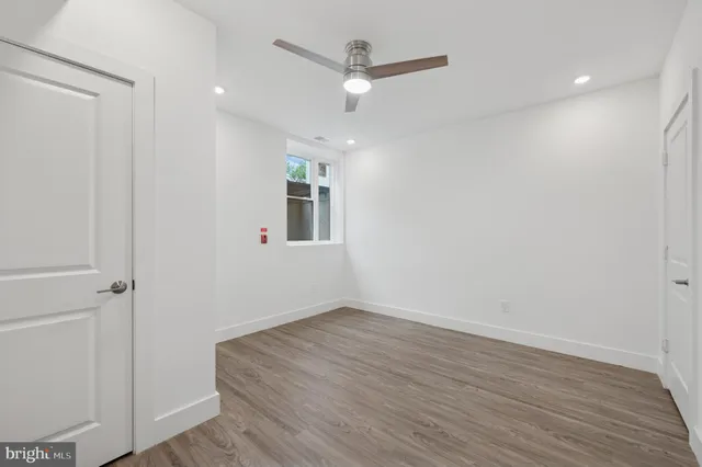an empty room with wooden floor and ceiling fan