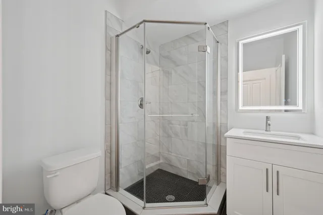 a bathroom with a shower sink vanity and toilet