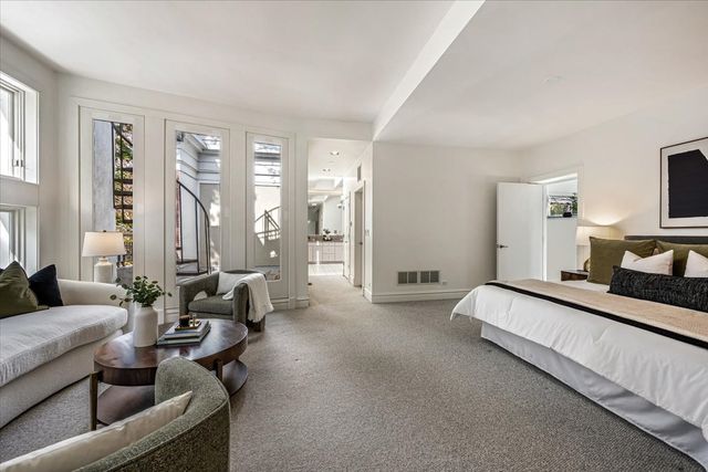 a spacious bedroom with a bed couch and windows