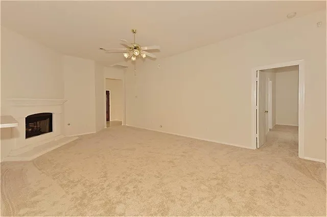 an empty room with chandelier fan and windows