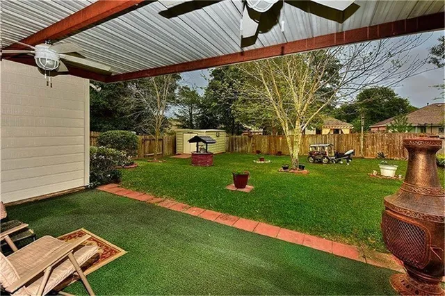 a view of a white house with a yard patio and a garden