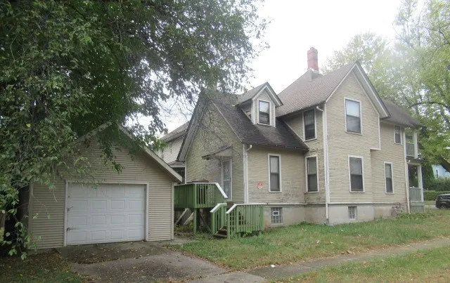 a view of a white house next to a yard and large tree