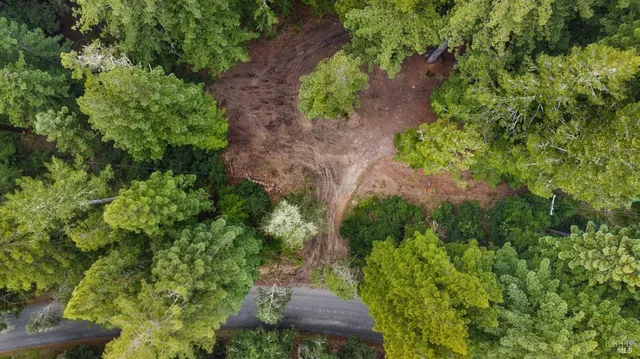 an aerial view of residential house with outdoor space and trees all around