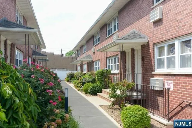 a view of a brick house with large windows and flower plants