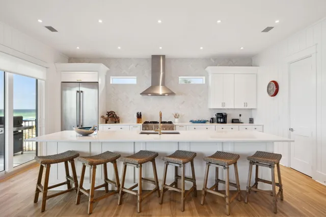 a kitchen with stainless steel appliances kitchen island granite countertop a dining table chairs and white cabinets