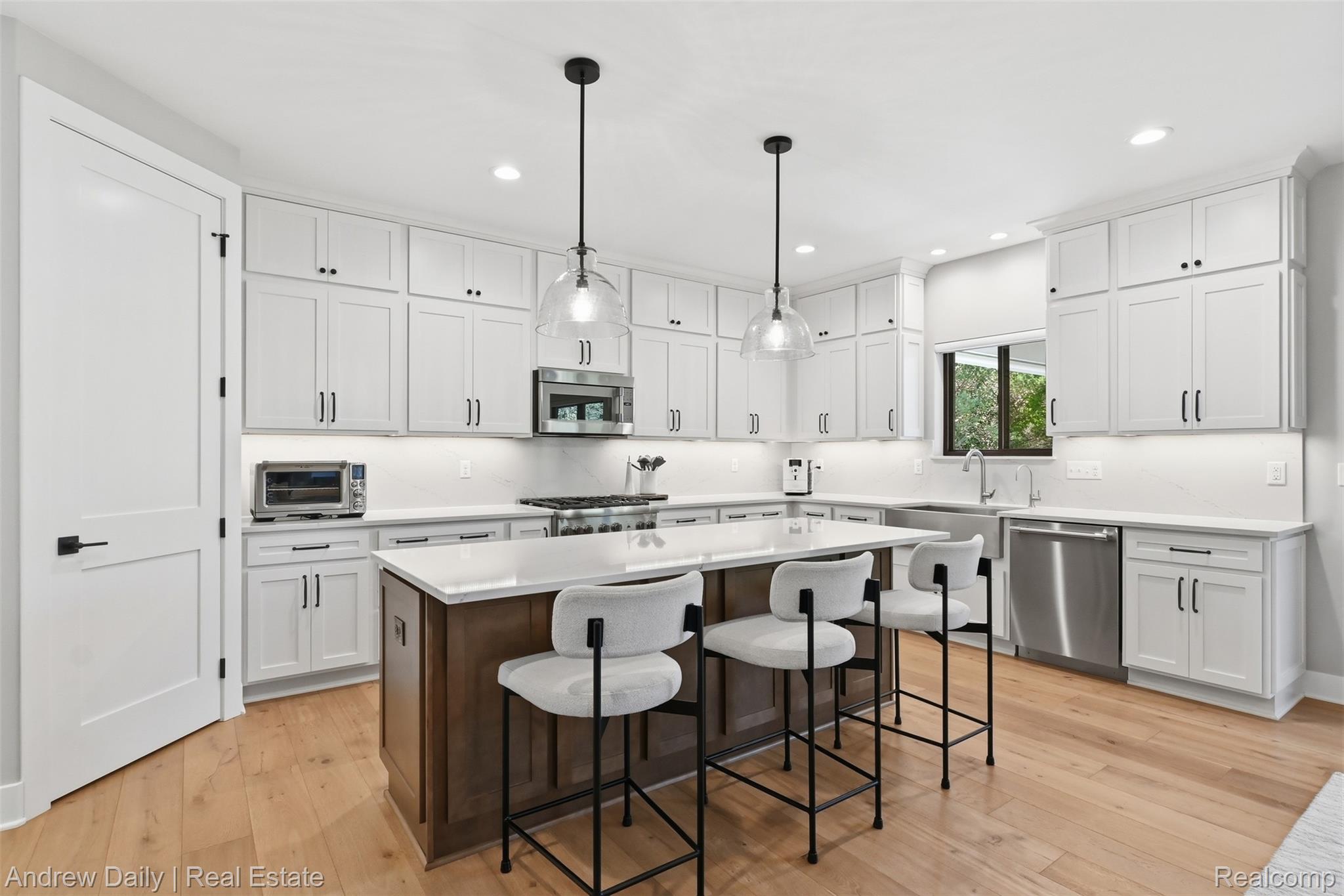 4661 Spears Road Pinckney, MI 48169 - Photo 20 of 56 Modern kitchen featuring a large central island, light wood-finish flooring, white shaker cabinetry, stainless steel appliances, and pendant lighting