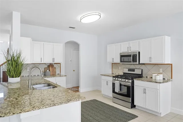 a kitchen with stainless steel appliances granite countertop a sink a stove and cabinets