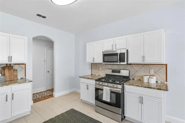 a kitchen with stainless steel appliances white cabinets and stove top oven