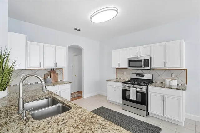 a kitchen with stainless steel appliances granite countertop a sink stove and cabinets
