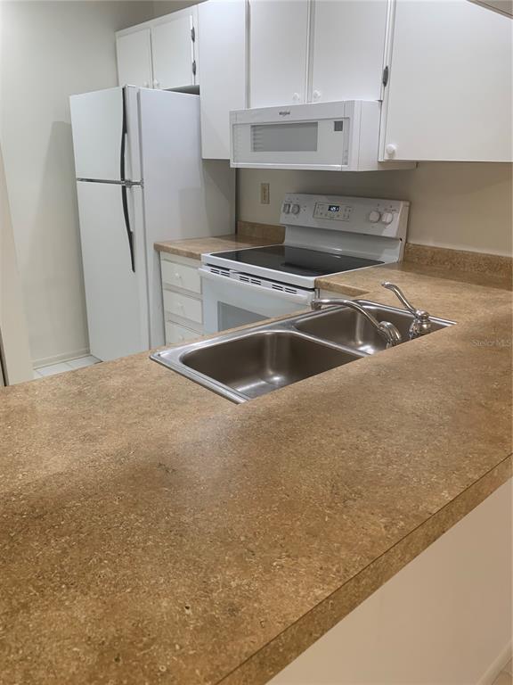 3223 South Beneva Road, Unit 103 Sarasota, FL 34232 - Photo 6 of 17 a kitchen with stainless steel appliances granite countertop a sink and a refrigerator